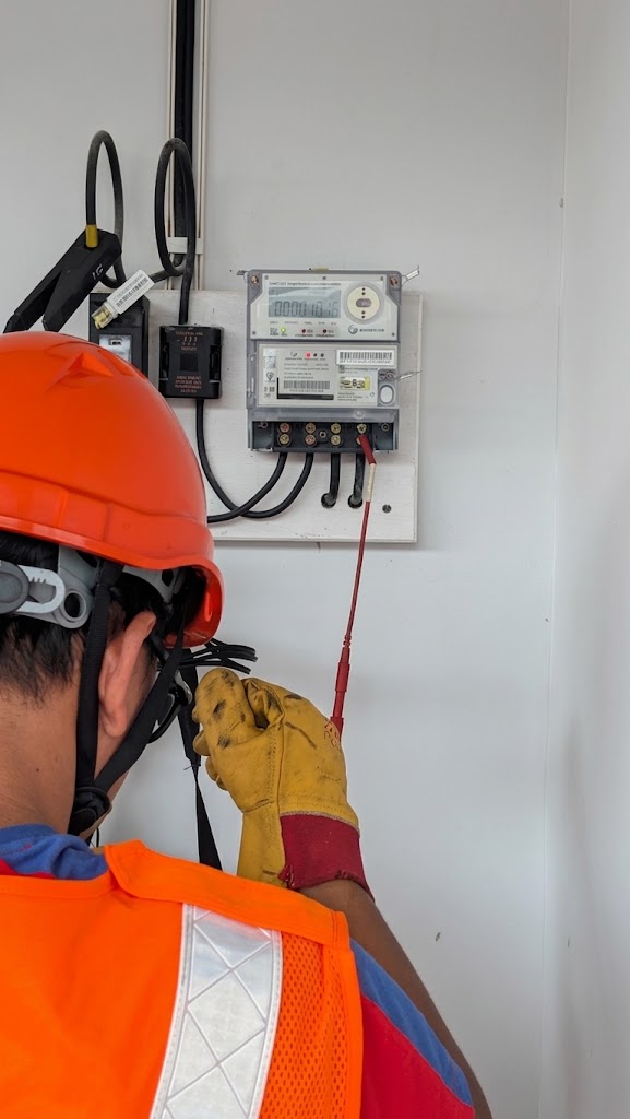 Field technician testing a wall-mounted smart meter during installation